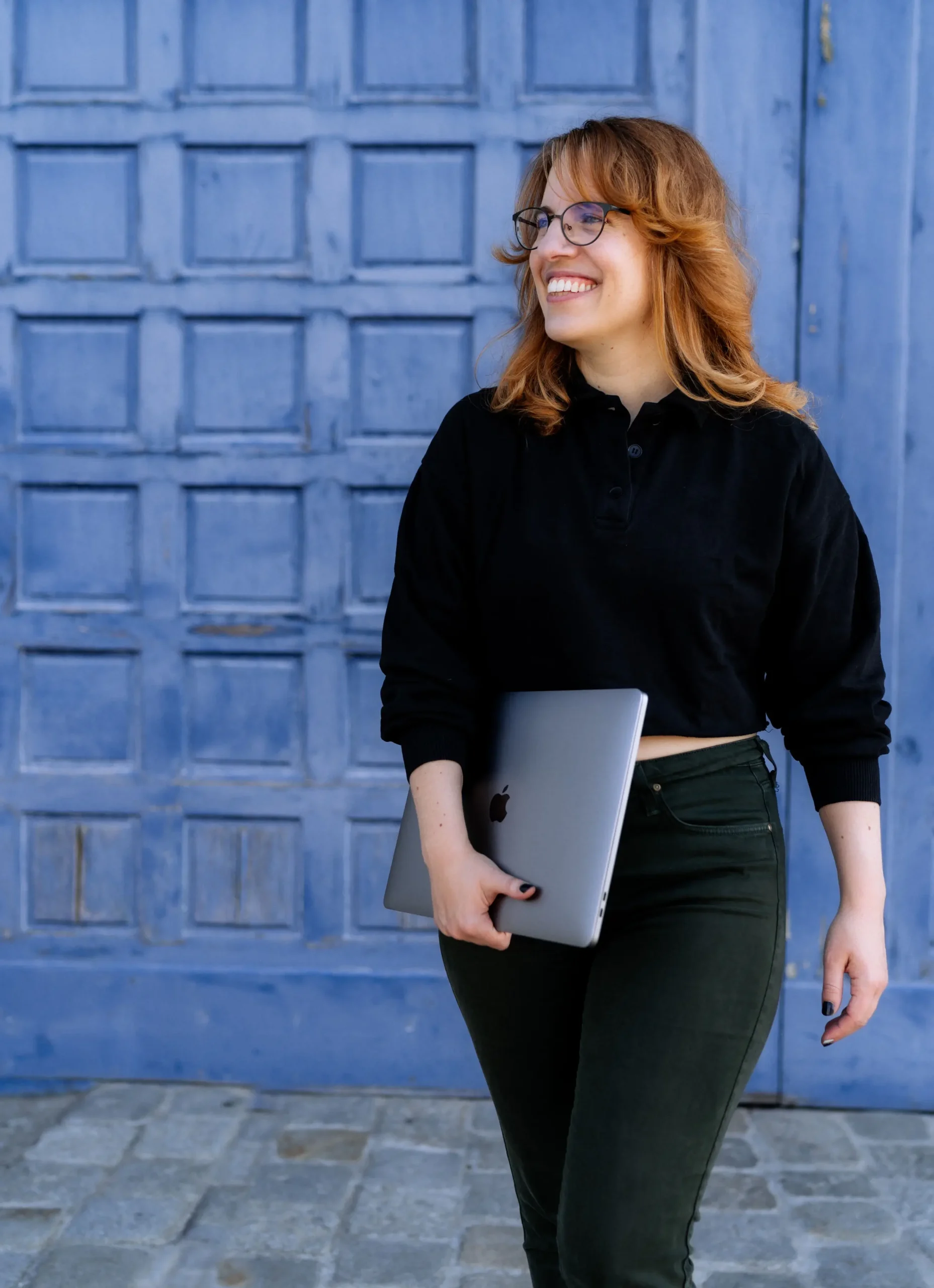 Sandra sitzt gelassen am Boden, ihre Hand liegt auf dem aufgestellten Bein. Sie lächelt und schaut auf ihr Handy.